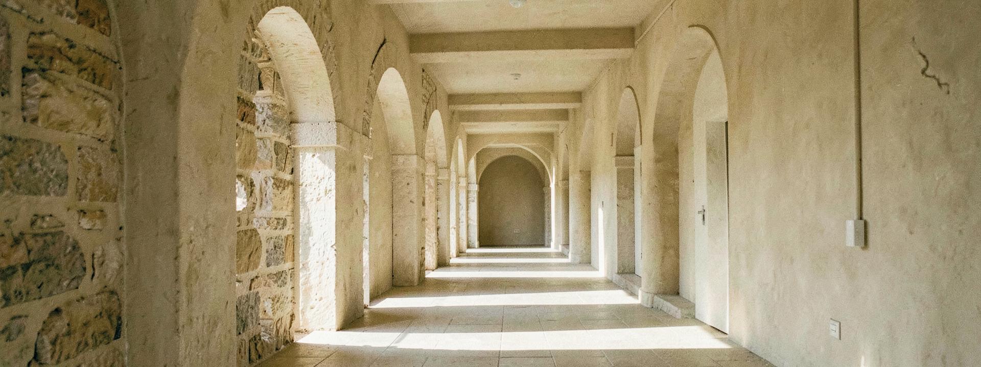 Sunlit stone corridor with repeating arches